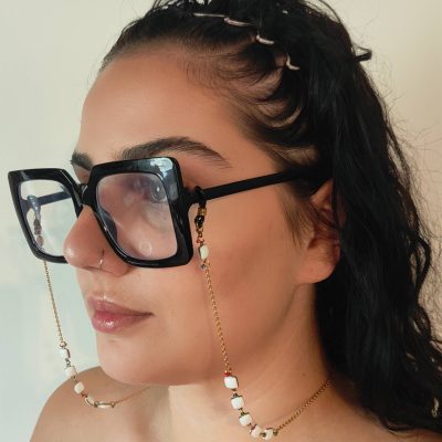 Chaîne à lunettes - Perles d'agate roses entourées et entrelacées de perles de rocailles dorées - présentée sur une jeune femme